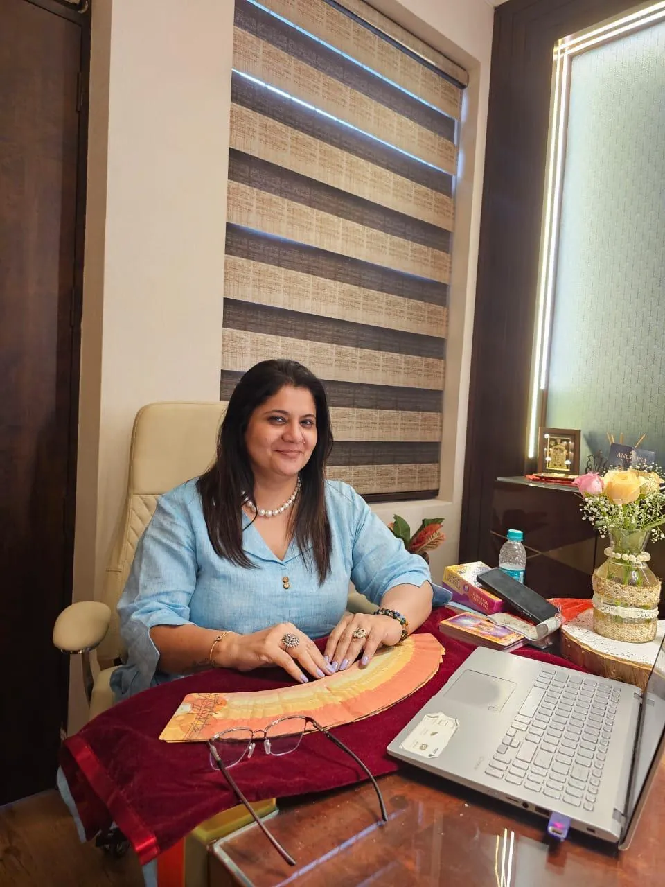 Sapnaa Khemani at her consulting desk, a fanned deck laid out beside her laptop