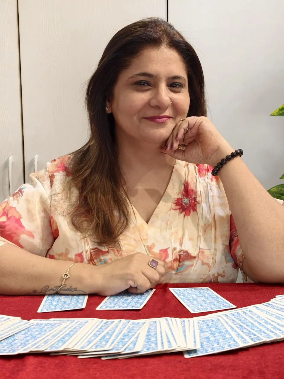Sapnaa Khemani resting her chin on her hand beside a three card spread