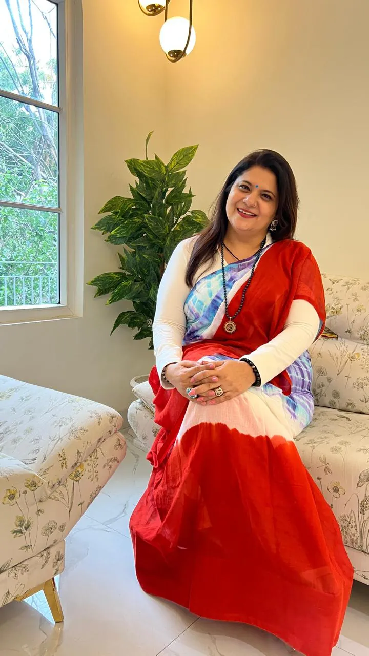 Sapnaa Khemani seated with her hands folded, in a red and white saree