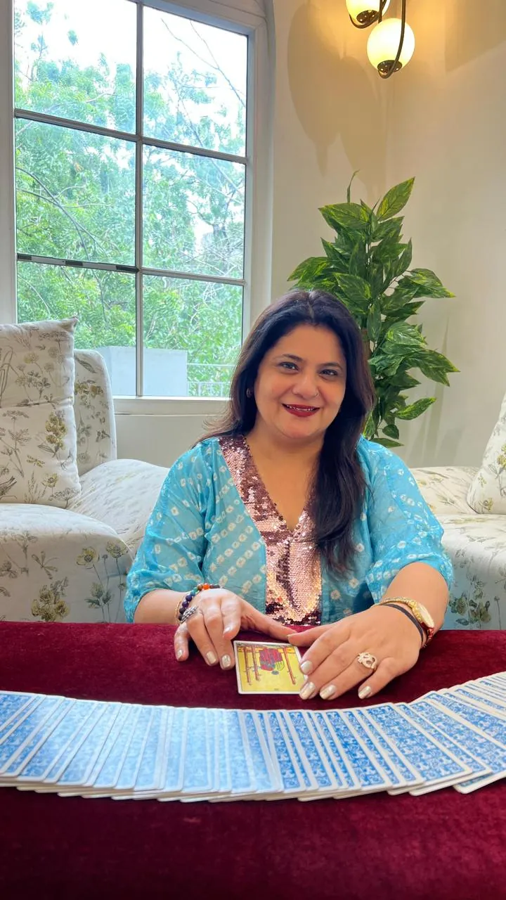 Sapnaa Khemani drawing a card from the fanned deck, in a turquoise sequinned kurta